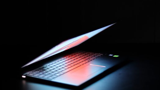 A laptop computer, slightly open, bathed in a red glow